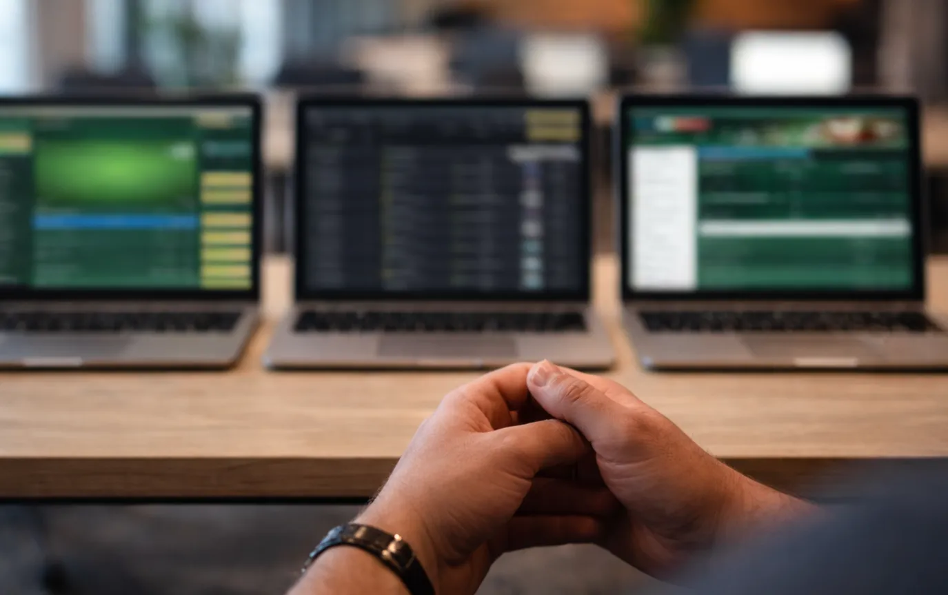 Drei verschiedene Laptop-Bildschirme zeigen unterschiedliche Wettplattform-Typen